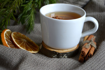 Cup of lemon tea, dried oranges, cinnamon, fir branch. Winter holidays concept. Cozy home