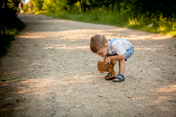 Little boy raises teddy bear on the footpath