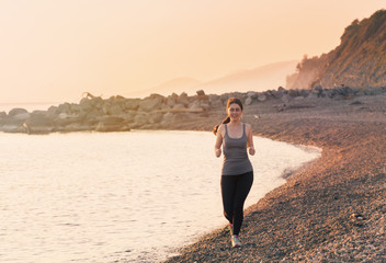Beautiful young women jogging on the coast. Healthy lifestyle. Sunset on the sea at the background