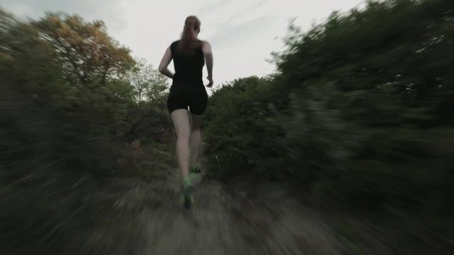 A female cross country runner training on a narrow beach trail by sunset in the summer.