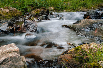 Flowing Water cascade of Mountain River with Bed Stones streaming down in the forest