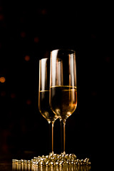 New Years Eve celebration background with pair of flute,candles glitter and defocused background, with christmas tree light forming a nice bokeh, holiday concept, frontal view,,copyspace