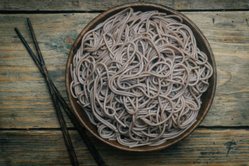 Soba noodles in a wooden bowl on a wooden background. Japanese style. Zen food.