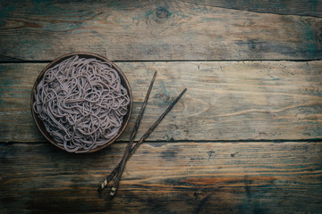 Soba noodles in a wooden bowl on a wooden background. Japanese style. Zen food. Copy space.
