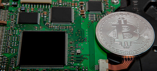Close-up of bitcoin, computer circuit board with bitcoin processor and microchips. Electronic...