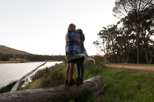 Couple wrapped in blanket standing at campsite
