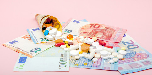The tablets wrapped in euro with euro banknotes on a pink background. Medical concept
