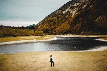 Mann mit Hut und Rücksack steht am Lödensee bei Ruhpolding und blickt in die ferne in den bayerischen Alpen