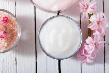 beauty and cosmetic creams with pink flowers on white wood