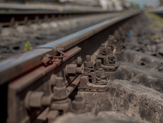 Selective field of focus. Detail of rusty screws and nut on old railroad track. Concrete tie with rusty nuts and bolts. Damaged surface of rail rod. No train passed this railroad for a long time