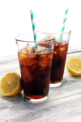 Softdrink with ice cubes, lemon and straw in glass