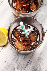 Softdrink with ice cubes, lemon and straw in glass