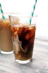 Ice coffee on a rustic table with cream being poured into it showing the texture and refreshing look of the drink