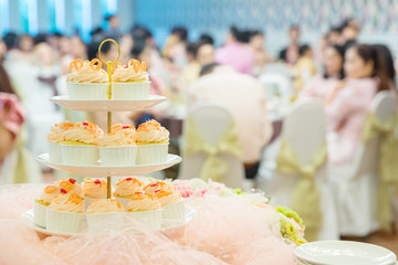 many cupcakes on shelf shelves in wedding party. dessert serving for wedding guest. sweets mini cakes.