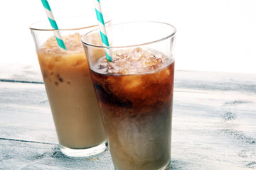 Ice coffee on a rustic table with cream being poured into it showing the texture and refreshing look of the drink