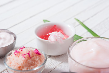 beauty and cosmetic creams with pink flowers on white wood