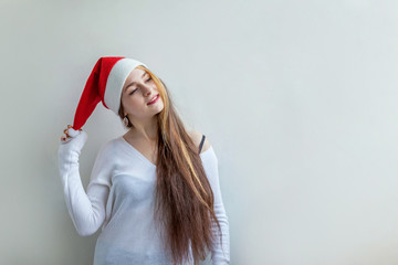 Beautiful girl with long hair in red Santa Claus hat isolated on white background looking happy and excited. Young woman portrait, true emotions. Happy Christmas and New Year holidays