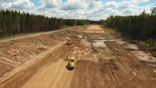 Construction of a new road in the forest area. Aerial view construction road place. Construction machinery for the construction of a road in the forest. 4K, flying video, aerial footage