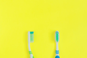Two toothbrushes  on yellow background. Top view, minimal flat lay.