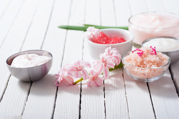 beauty and cosmetic creams with pink flowers on white wood