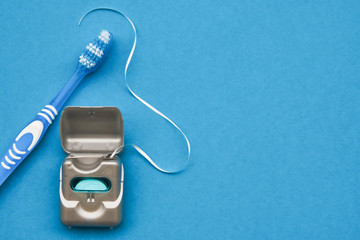 Dental floss and toothbrush on a blue background with copy space