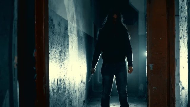 man maniac or killer or horror murderer with knife in hand in dark creepy and spooky corridor. Criminal robber or rapist concept in thriller atmosphere