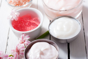 beauty and cosmetic creams with pink flowers on white wood
