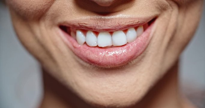 woman with pink lipstick on lips and perfectly white teeth beautifully smiling - extreme closeup 4k