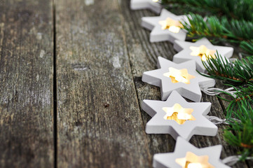 Christmas theme: cozy warm lights garland stars and fir branches on rustic wooden background. top view. over hand