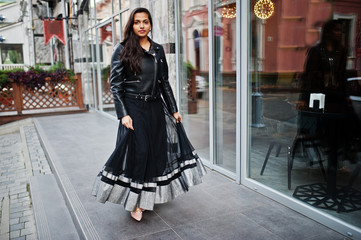 Naklejka premium Pretty indian girl in black saree dress and leather jacket posed outdoor at street.