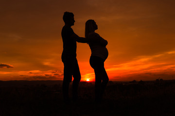 Fototapeta na wymiar Silhouettes of husband and pregnant wife having conflict while they standing outdoor.
