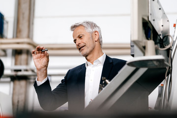 Manager in high tech enterprise, checking machine parts