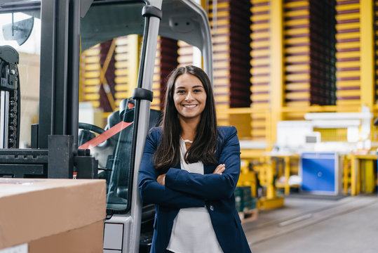 Confident woman standing in logistics center, with arms crossed