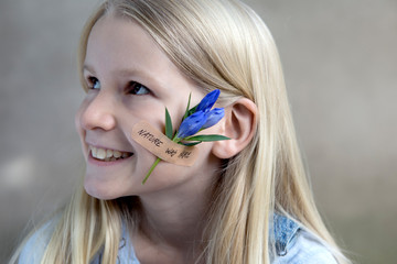 Portrait of smiling blond girl with flower head on her cheek
