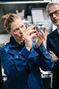 Manager and skilled worker in high tech enterprise, checking machine parts