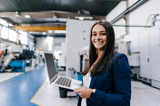 Confident woman working in high tech enterprise, holding laptop