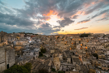 Fototapeta na wymiar Night approaches as the sun sets in the Puglia region as the the ancient homes, sassi and abandoned buildings fill the hillside of Matera, Italy.