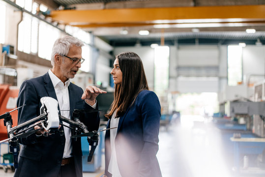 Businessman an woman in high tech enterprise, discussing production of drones