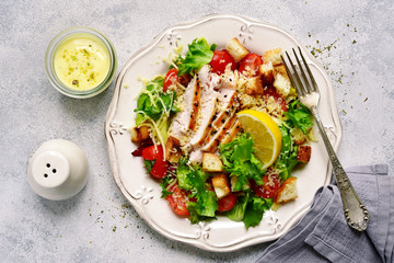 Caesar salad with grilled chicken, parmesan cheese, croutons and cherry tomatoes.Top view with copy space.