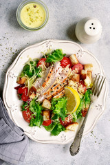 Caesar salad with grilled chicken, parmesan cheese, croutons and cherry tomatoes.Top view with copy space.