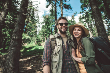 Concept of life activity in couple. Waist up portrait of man and woman looking happy while travelling together uphill in forest. Copy space on left