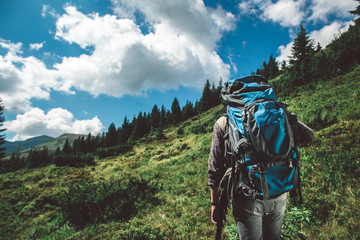 Concept of breathtaking journey and adventure. Back side portrait of young man climbing up of green hill of mountain. Copy space on left