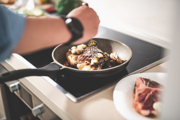 Close up of male hand holding fork near appetizing roasted meat on frying pan