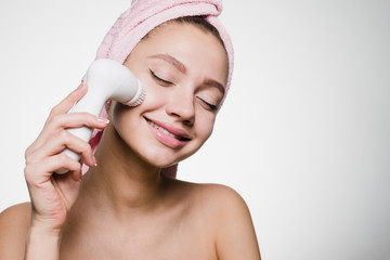 happy smiling girl with a pink towel on her head doing a deep cleansing of her face with an...