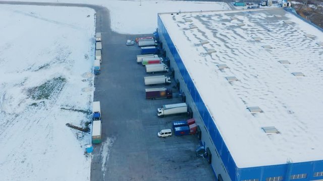 Aerial look-down view of a warehouse logistics terminal with parked cargo trucks in winter day