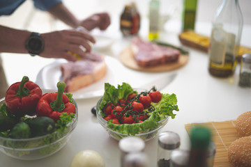 Close up of bowls with tomatoes, lettuce, cucumber and red bell pepper on kitchen table
