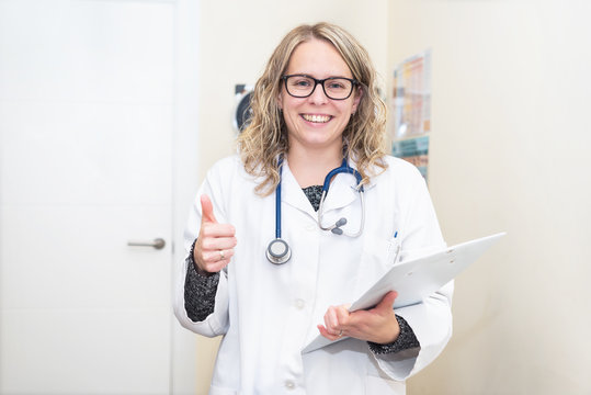 Portrait of a young female doctor showing thumbs up, positive emotion.