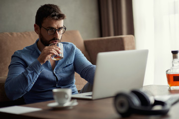 Young man works for a computer from a home with a laptop   as a freelancer.