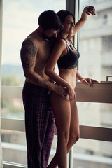 Couple after sex, standing next window.