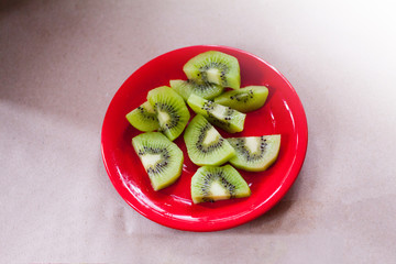 Fresh green kiwi on red plate